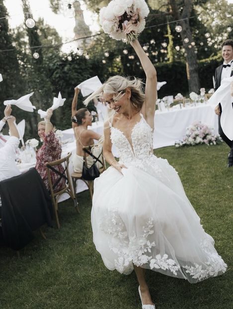 Real Bride feiert im Tüllkleid mit erhobenen Armen – White Silhouette München