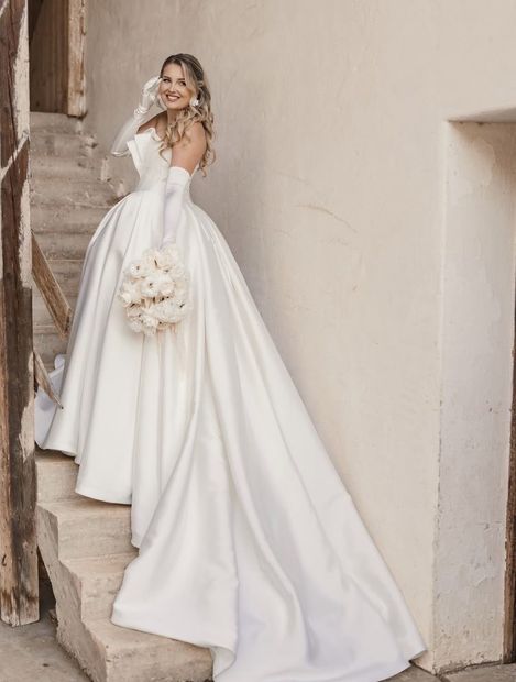 Real Bride in großer Satin-A-Linie mit Strauß auf der Treppe – White Silhouette München