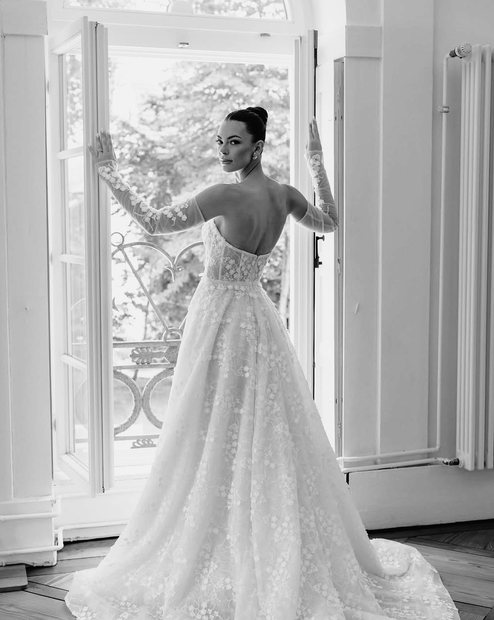 Real Bride dreht sich im Satin-Brautkleid, zwei Begleiterinnen applaudieren im Hintergrund