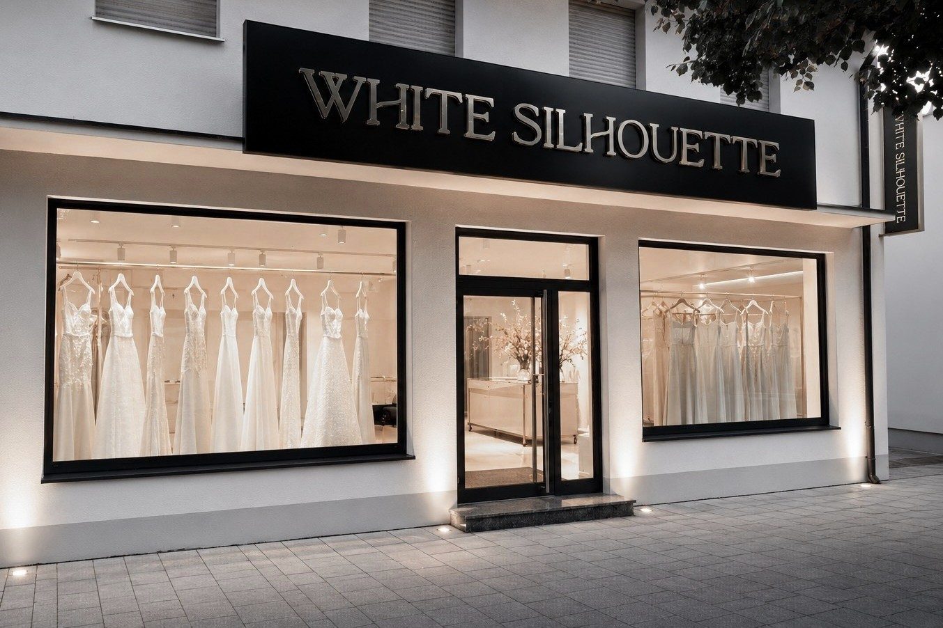 Beleuchtete Schaufenster des Brautmodengesch&auml;fts White Silhouette in M&uuml;nchen am Abend, dahinter Brautkleider auf Stangen